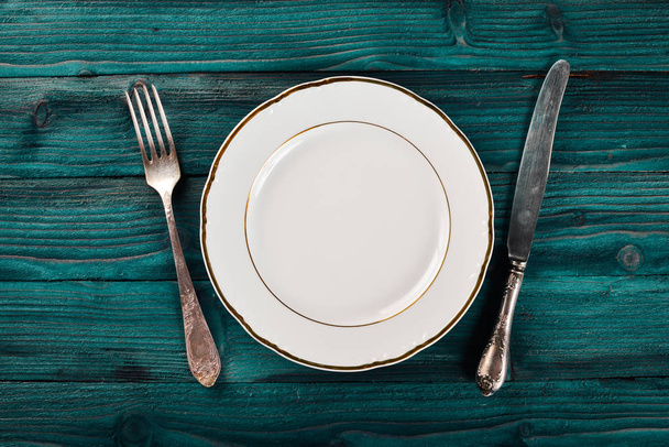 Plate and old cutlery. On a wooden background. Top view. Free space for text. - Photo, image