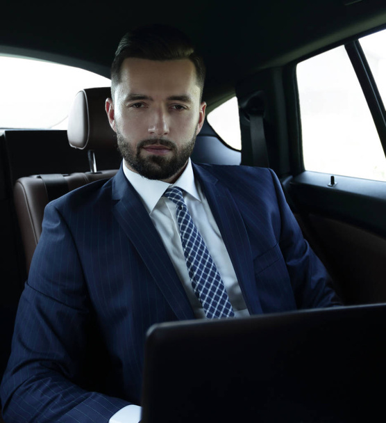 бизнесмен с ноутбуком сидит в комфортабельной машине
 - Фото, изображение