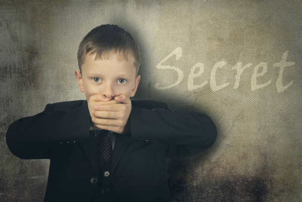 Boy closed his mouth with his hand and keeps a secret. - Photo, Image