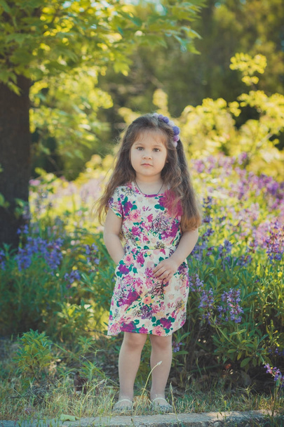 colourful summer scene of cute runette young girl child enjoying free time in wild forest flowers field wearing stylish tiny dress on sunny meadow - Photo, Image