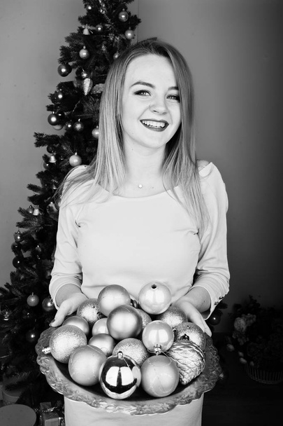 Cute blonde girl on beige dress against new year tree with with  - Fotografie, Obrázek
