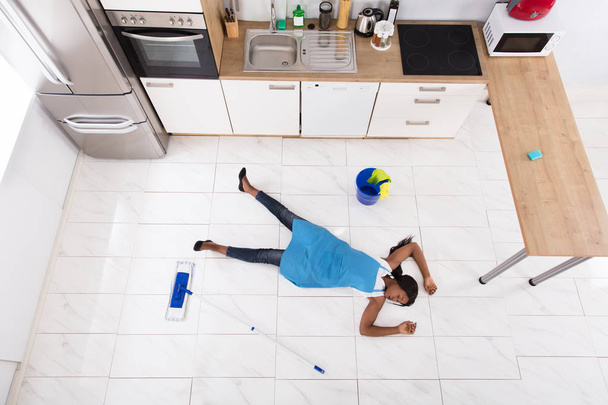 Femme au foyer allongé sur le plancher de la cuisine
 - Photo, image