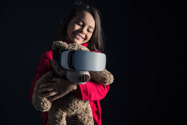Kind setzt Kopfhörer auf Teddybär  - Foto, Bild