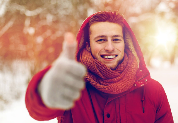 happy man in winter jacket showing thumbs up - 写真・画像