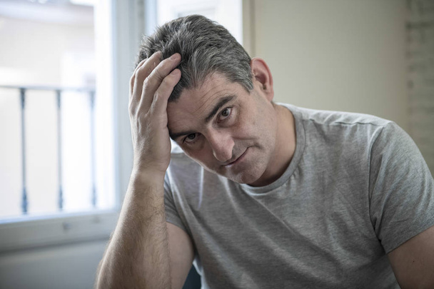 sad and worried man with grey hair sitting at home couch looking - Foto, immagini