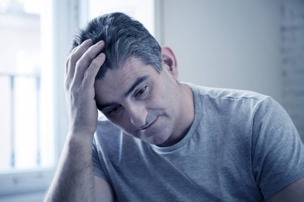 hombre triste y preocupado con el pelo gris sentado en el sofá de casa buscando
 - Foto, Imagen
