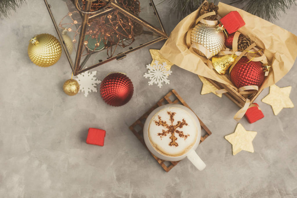 Top view flat lay White mug of cappuccino with cinnamon powder snowflake among christmas toys - Fotografie, Obrázek
