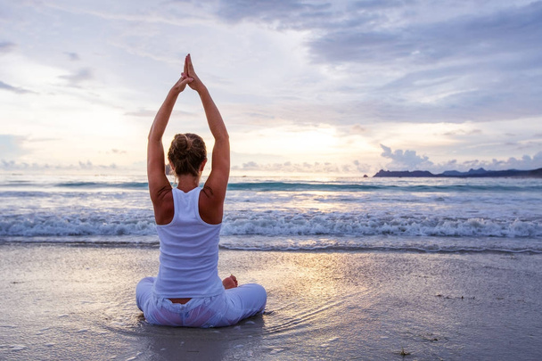 Mujer caucásica practicando yoga en la orilla del mar del océano tropical
 - Foto, Imagen