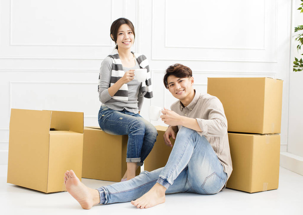 joven pareja llevando cajas en nuevo hogar y beber café
 - Foto, Imagen
