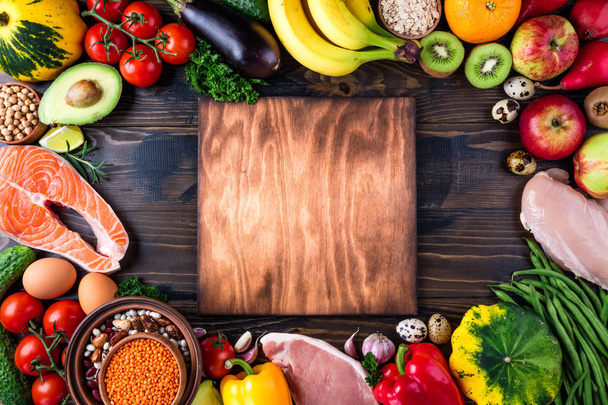 На задньому плані здорова їжа. Свіжі овочі, фрукти, м'ясо та риба на дерев'яному столі. Здорове харчування, дієта та здорове життя. Вид зверху
 - Фото, зображення