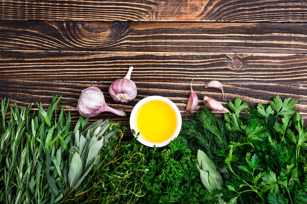 Čerstvé bylinky a koření, česnek, olivový olej na dřevěné pozadí. Zdravé potraviny a vaření koncepce. Zahradní bylinky - Fotografie, Obrázek