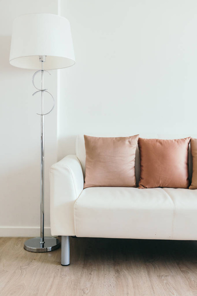 Cómoda almohada en sofá blanco con lámpara de luz
 - Foto, imagen