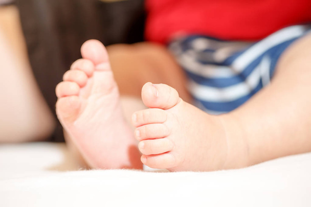 Close-up of beautiful baby feet sitting on the floor isolated on white background. - Foto, immagini