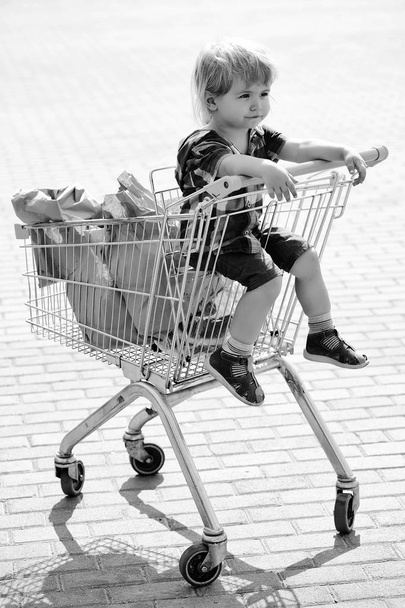 Cute boy in shopping trolley - Fotó, kép