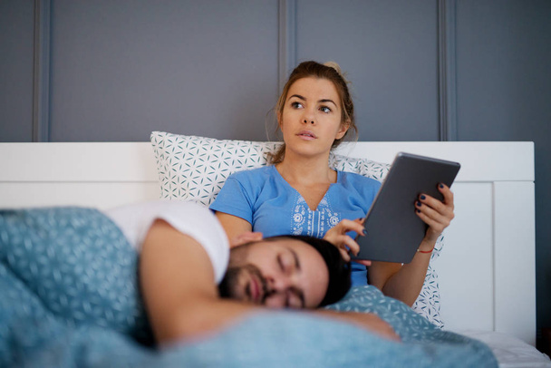 woman using tablet and boyfriend sleeping  - Фото, зображення