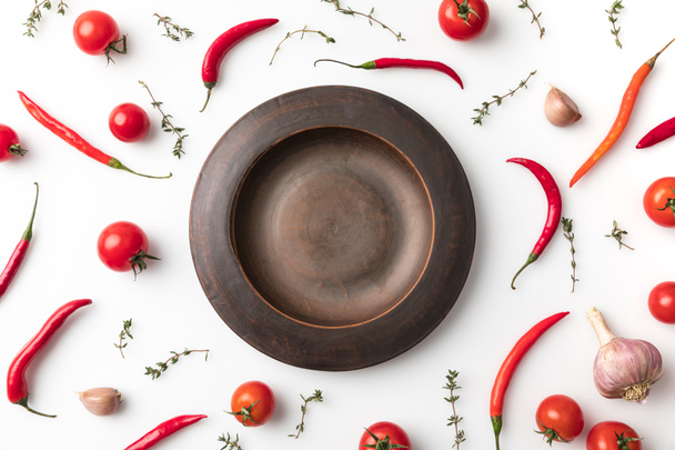 plate among chili peppers and tomatoes  - Valokuva, kuva