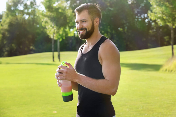 Sporty young man with protein shake outdoors - Valokuva, kuva