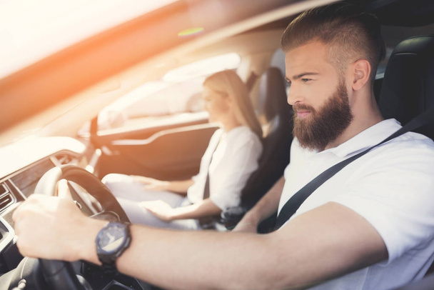 A young man with a beard sits at the wheel of an electric vehicle. - 写真・画像