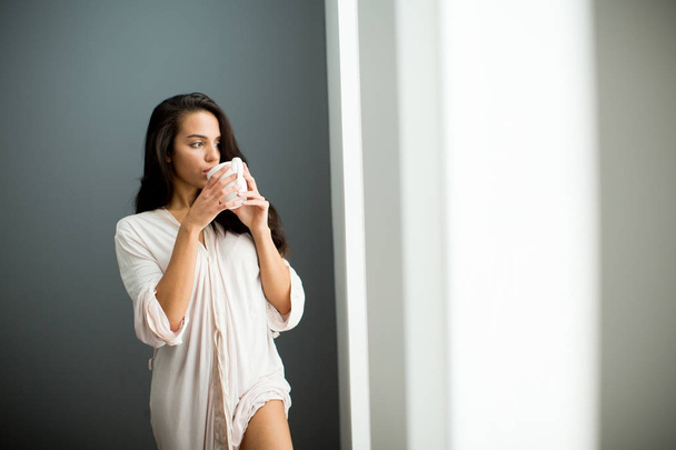 Giovane donna con tazza in camera da letto
 - Foto, immagini