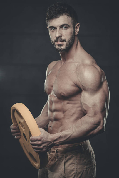 Handsome model young man training arms in gym - Foto, afbeelding