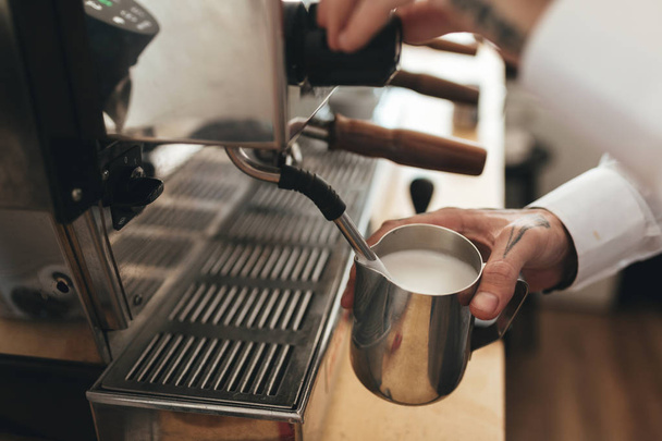 バリスタは、コーヒー ショップのカウンターでコーヒーを準備します。レストランでコーヒーのコーヒー マシンのミルクをホイップ男の手を閉じる - 写真・画像