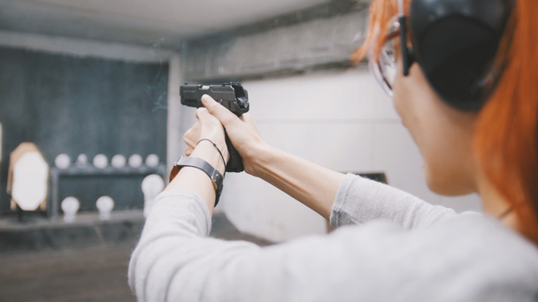 Woman shooting with a gun in shooting gallery - Фото, изображение