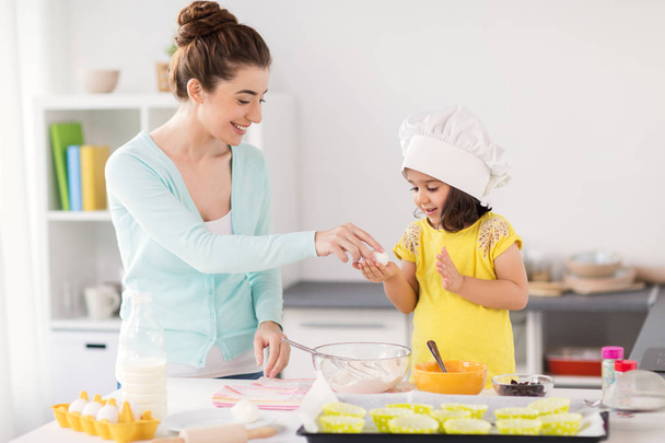 happy mother and daughter baking at home - Foto, afbeelding