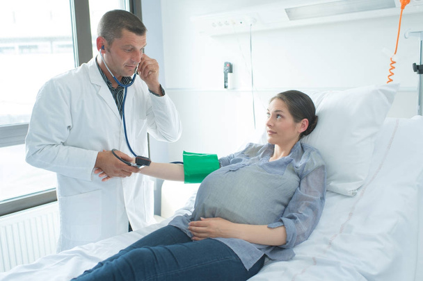 Doctor taking pregnant woman's blood pressure - Foto, imagen