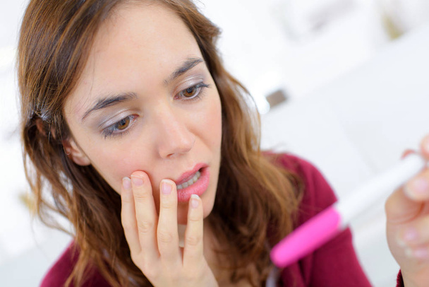 Anguished woman looking at pregnancy tester - Foto, immagini