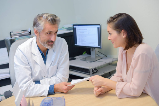 Doctor handing prescription to female patient - Photo, Image