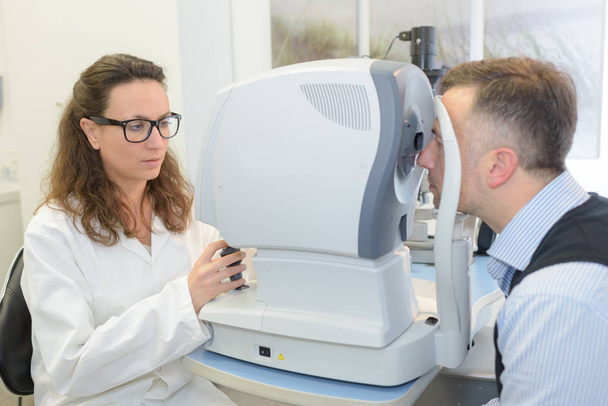 optometrist does an eye exam on patient - Foto, afbeelding
