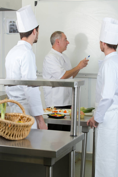 chef writing recipe on a board for apprentices - Foto, immagini