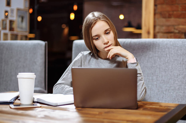 Young beautiful woman is using laptop in a cafe - Photo, image