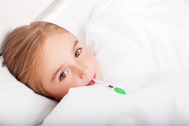 Grippe. Jeune fille couchée au lit avec un thermomètre
 - Photo, image