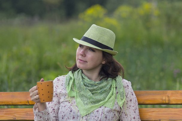 Mujer en un sombrero y con una taza durante el resto. Gente
 - Foto, imagen