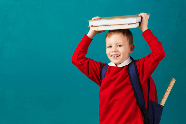 Cheerful thoughtful little school boy in school uniform with bac - Foto, afbeelding
