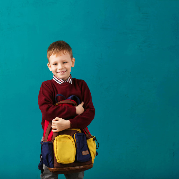 Веселый вдумчивый маленький школьник в школьной форме с большой
 - Фото, изображение