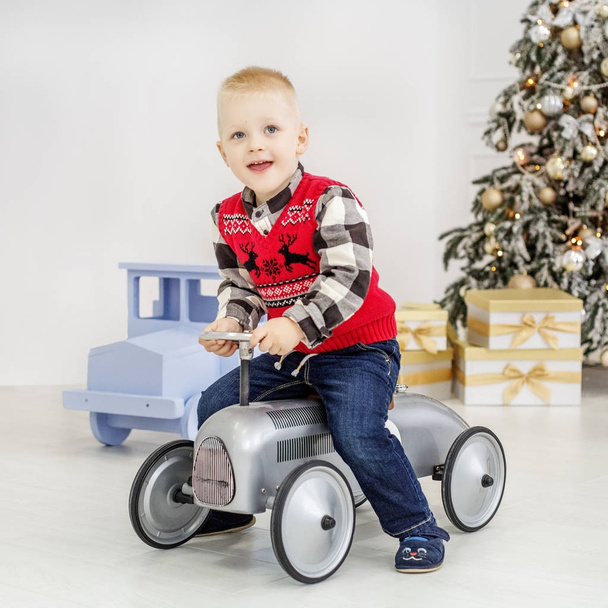 A little boy rides on a toy car. Concept Happy Christmas - Photo, Image
