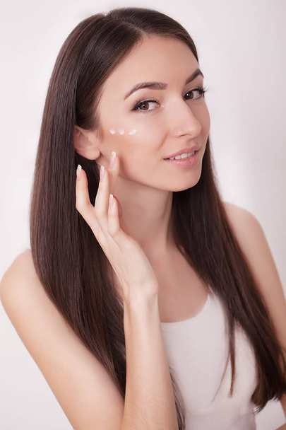 Attractive girl putting anti-aging cream on her face - Photo, Image