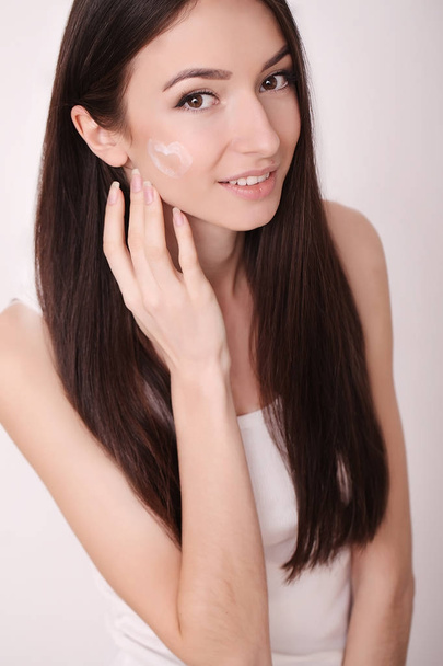 Attractive girl putting anti-aging cream on her face - Фото, зображення
