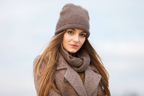 girl in a knitted cap and scarf in the autumn on nature. cold. - Photo, image
