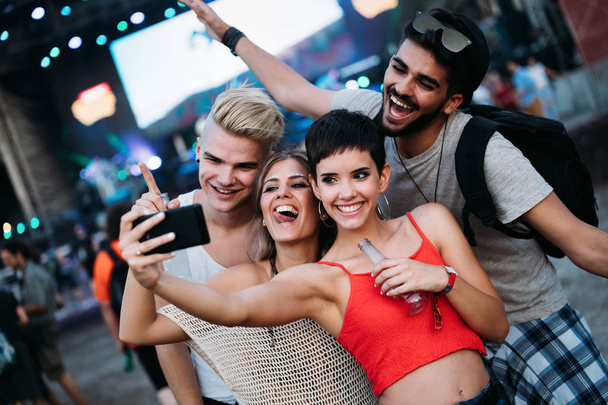 Happy young friends taking selfie at music festival - Фото, изображение