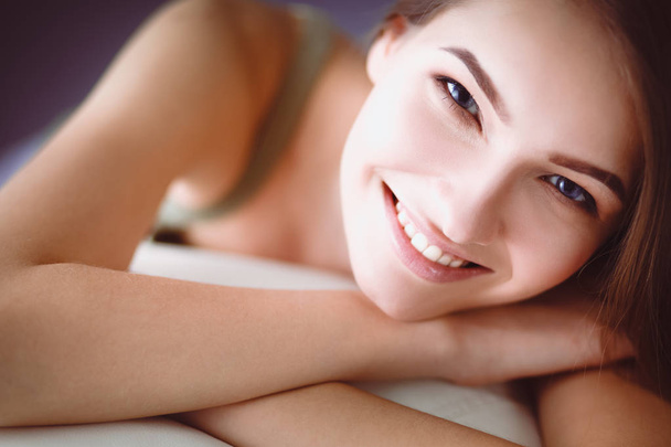 Closeup of a smiling young woman lying on couch - Фото, изображение