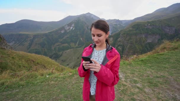 Una joven usando un teléfono inteligente en las montañas
. - Metraje, vídeo