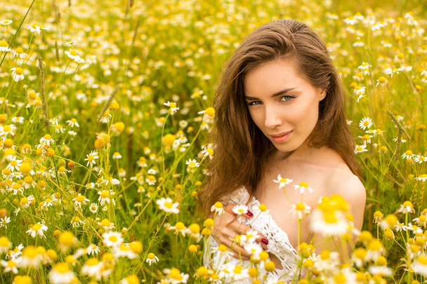 Sexy brunette young woman in chamomile field - Foto, immagini