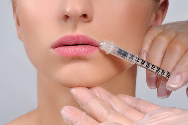Beautiful girl receiving filler injection in lips. Botox. Cosmet - Foto, afbeelding