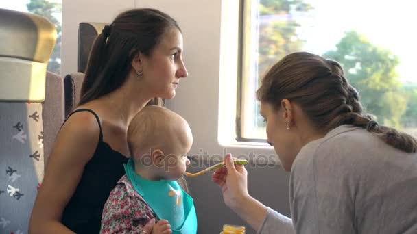 Two Young Ladies Feeding a Baby on the Train - Кадри, відео