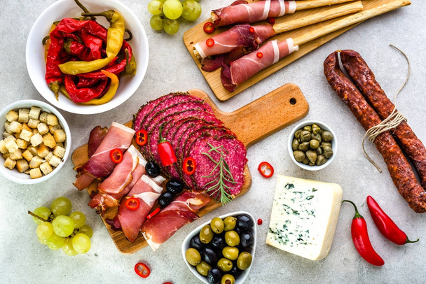 Traditional spanish tapas on table, food selection, cold meat, sausage, spicy chorizo, salami slices, ham and other snack on platter - Fotó, kép