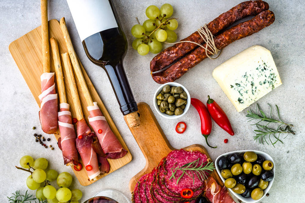 Variety food on table, wine, cheese and meat, cold traditional tapas for mediterranean menu - Фото, изображение