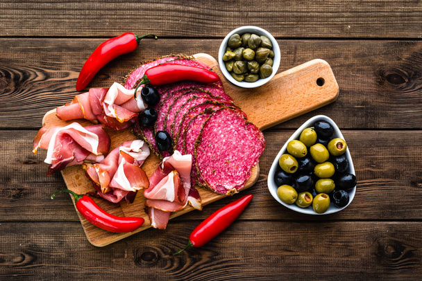 Assiette de viande froide avec salami, tranches de jambon prosciutto, antipasti italien sur planche de bois
 - Photo, image